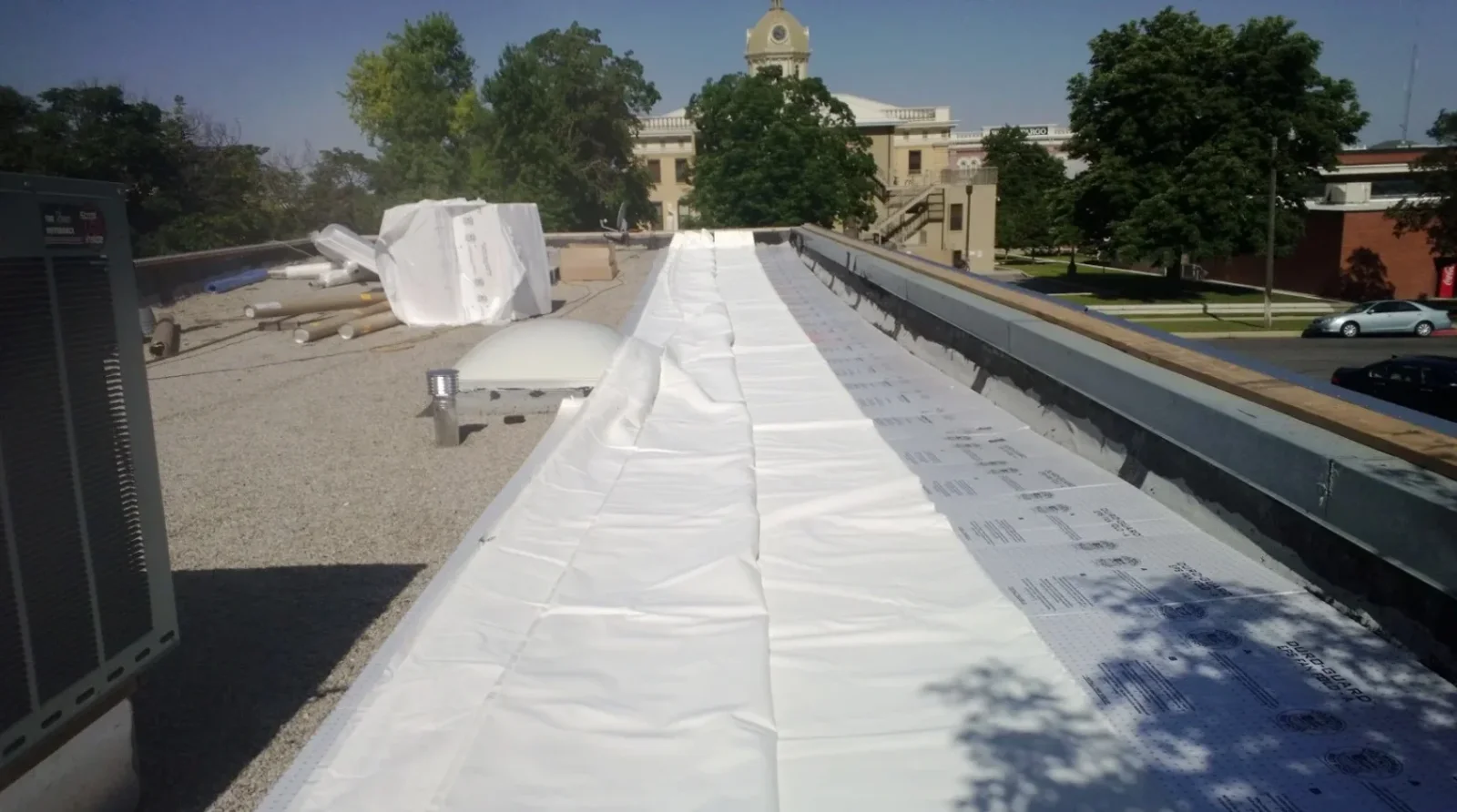 White TPO membrane flat roof installation with seams and weatherproofing on commercial building