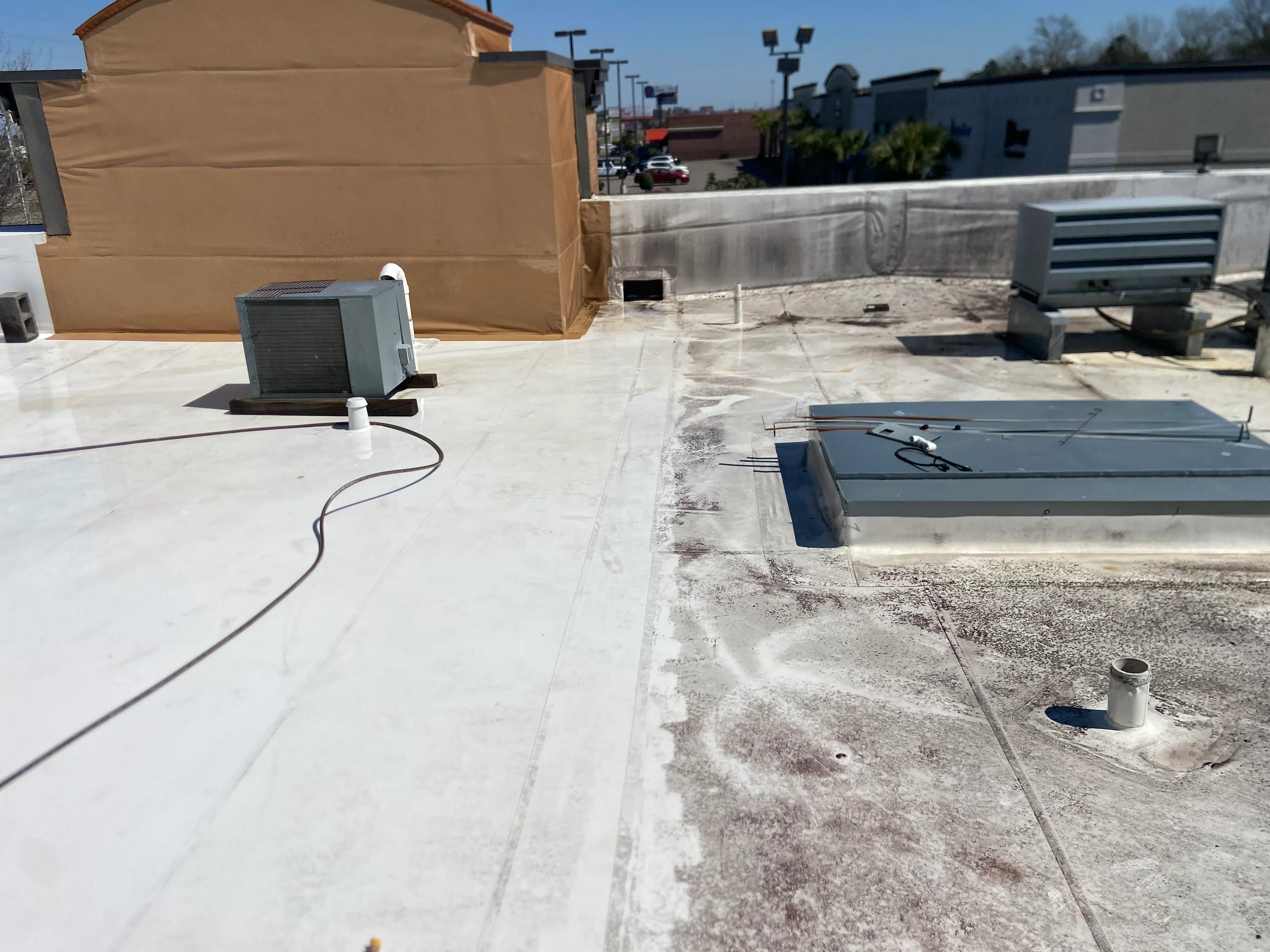 White membrane flat roof with HVAC units, flashing, and drainage systems on commercial building